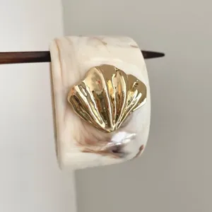 Elegant resin hair cuff with gold shell ornament and wooden hair stick for stylish buns.