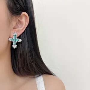 Detail of green zircon cross earrings closeup showcasing exquisite craftsmanship and shiny stones.