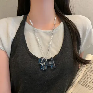Primo piano dettaglio della collana con ciondolo cucciolo blu trasparente e catena di perle.