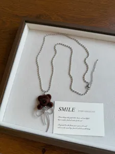 Cute fuzzy bear pendant necklace with silver bead chain and bow accessory for women.