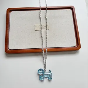 Primo piano dettagliato del ciondolo per cucciolo in resina blu e della collana di perle.