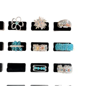 Close-up details of assorted blue crystal and silver rings displayed neatly on black velvet slots.