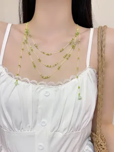 Multi-layer green beaded necklace detail showcasing irregular stone pendants and delicate strings.