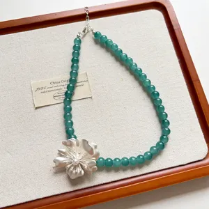 Vista dettagliata dell'elegante catenina di perle verdi con ciondolo floreale in argento.