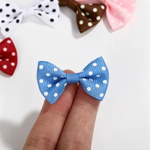 Macro detail of a mini blue polka dot ribbon bow being held for DIY accessory sizing.