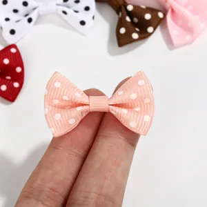 Detail shot of a mini pink polka dot ribbon bow held between fingers for DIY crafts