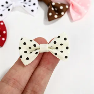 Close-up of a mini white polka dot grosgrain ribbon bowtie for DIY crafts.