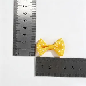 Macro view of yellow polka dot ribbon bow with a steel ruler showing exact size