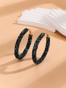 Detailed close-up of large hoop earrings encrusted with sparkling black iridescent rhinestones.
