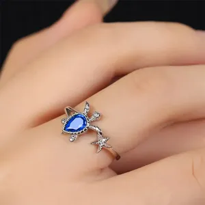 Detail shot of a cute ocean-themed turtle and starfish ring with a blue crystal gem.