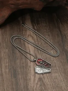 Collana con ciondolo bara gotica con dettaglio scheletro smaltato rosso su sfondo di legno.
