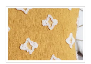 Close-up detail of yellow textured cotton linen pillow cover with white tufted geometric pattern.