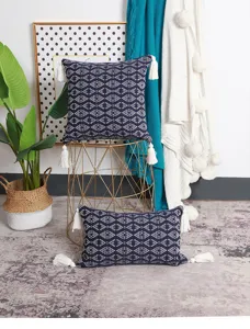 Detailed shot of bohemian woven cushion covers with geometric patterns and white tassels.