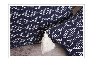 Close-up detail of navy blue woven throw pillow with white geometric pattern and elegant tassel.
