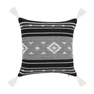 Schwarz-weißer gewebter Kissenbezug mit boho-geometrischem Muster und Quasten an Ecken.