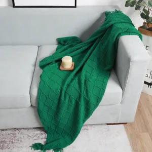 Manta de punto verde con patrón de rombos y flecos, ideal para el sofá del hogar.
