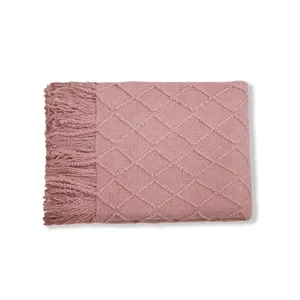 Hermosa manta de punto rosa con elegante patrón de rombos y flecos para sofá y cama.