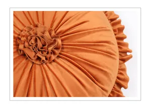 Velvet round throw pillow detail, rust orange pleated flower design with ruffled edge.