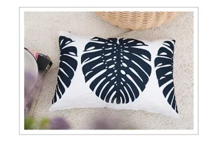 Detail shot of black and white monstera leaf patterned cotton linen throw pillow cover.