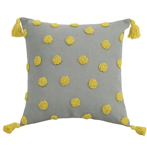 Nordic style grey throw pillow cover with yellow tufted polka dots and four corner tassels.