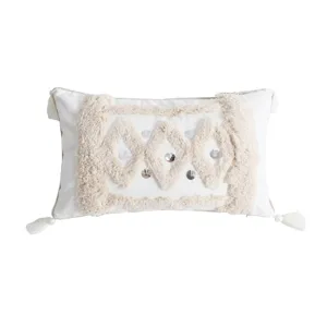 White tufted throw pillow cover with bohemian geometric diamond patterns and decorative tassels for sofa.