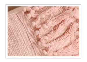 Close-up van de roze kussenhoes met geweven textuur en mooie decoratieve franjes.