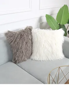 Detail shot of fluffy long hair plush pillow covers in grey and white on a modern sofa.