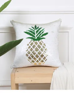 Close-up detail of the golden pineapple sequin throw pillow on wooden stool, home decor.