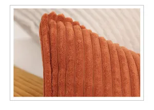Close-up of retro orange corduroy pillow cover texture, soft fabric stripe detail for sofa decor.