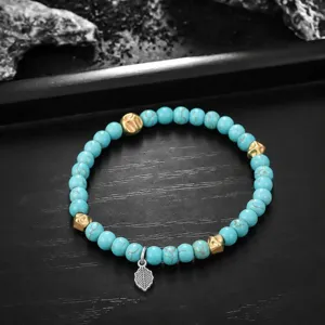 Gros plan sur le bracelet de perles turquoise avec perles dorées et pendentif feuille.