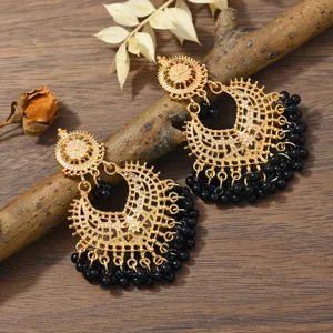 Close up shot of bohemian gold hollow carved earrings featuring elegant black beaded fringes