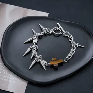 Gros plan d'un bracelet de chaîne à pointes en métal punk avec pendentif croix marron.