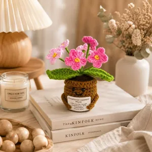 Detalle de planta en maceta de ganchillo, lindas flores rosas con tarjeta para decor.