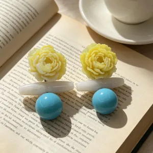 Detailed shot of artistic retro gradient yellow flower resin earrings with blue bead pendants.