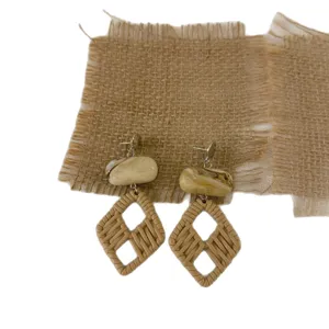 Close-up of bohemian style woven rattan geometric drop earrings with marble resin stone detail.