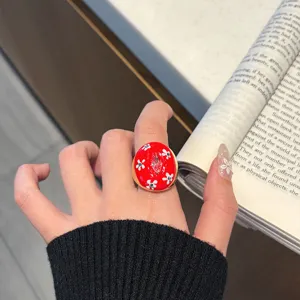 Detailed view of retro red oil-drop open metal ring with white floral and crystal charm.