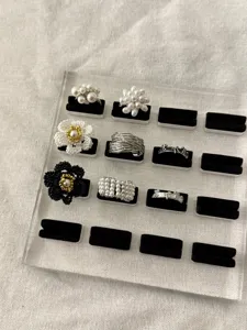 Vista dettagliata di anelli coreani stile ins con perle e fiori su supporto in acrilico.