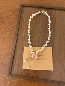 Detailopname van de roze rozen parelketting met delicate kralen en een romantische stijl.