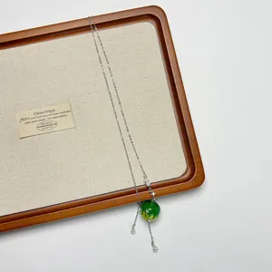 Close-up detail of the niche green apple pendant necklace, featuring delicate silver chains.