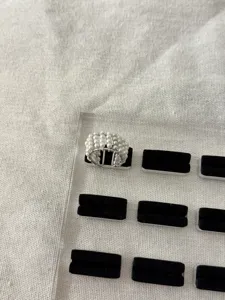 Primo piano del delicato anello aperto di perle multistrato con tessitura di fili fini.