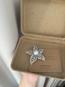 Detail view of a stunning rhinestone starfish brooch with a central pearl, elegant accessory.