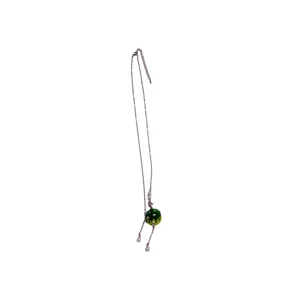 Close-up detail of the green apple pendant necklace with delicate chain and pearls.