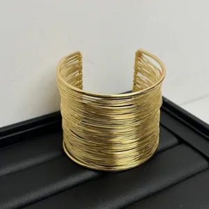 Close up detail of gold multi strand wire cuff bracelet showing metallic texture and design.