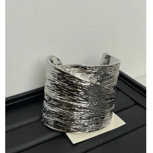 Detailed shot of a bold silver metal wide cuff bracelet with unique textured surface finish.