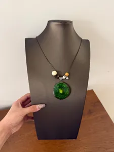 Detail view of the green kiwi fruit slice resin pendant necklace with wooden beads on cord.