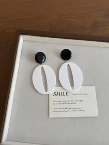Vintage style statement earrings with black round studs and white hollow resin drops for chic.