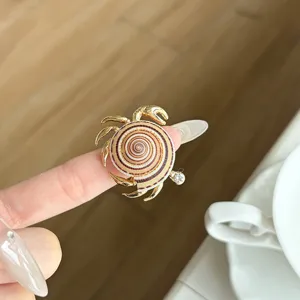 Close-up detail of a stylish metal open ring featuring an ocean crab and shell design.