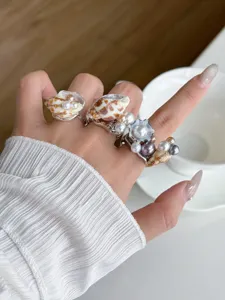 Wunderschöne Detailaufnahme von eleganten Perlen Muschel Ringen an der feinen Hand.