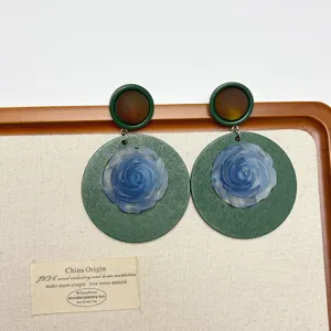 Vintage green wooden earrings featuring translucent blue frosted rose floral details and amber studs.