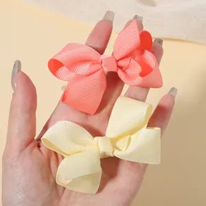 Détail des pinces à cheveux en ruban gros-grain corail et crème pour les enfants
